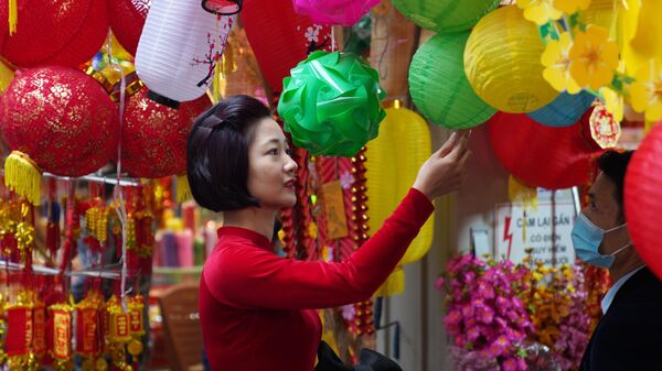 Девушка на рынке новогодних сувениров, украшений для дома и красочных цветов на центральной улице Ханоя