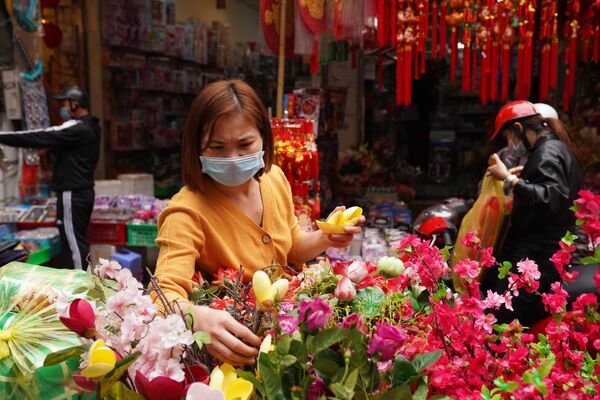 Девушка на рынке новогодних сувениров, украшений для дома и красочных цветов на центральной улице Ханоя