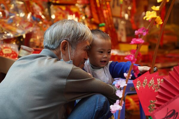 Мужчина с ребенком на рынке новогодних сувениров и украшений для дома на центральной улице Ханоя