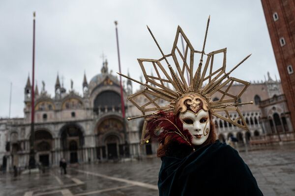 Человек в карнавальном костюме на площади Святого Марка в Венеции