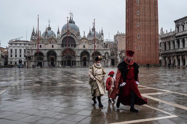Люди в карнавальных масках и костюмах на площади Святого Марка в Венеции