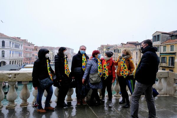 Туристы в красочных галстуках на мосту Риальто, во время ежегодного венецианского карнавала, который был отменен в этом году из-за пандемии коронавирусной инфекции в Венеции, Италия