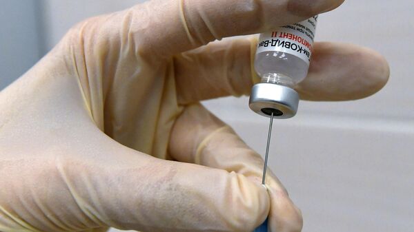 Медсестра набирает в шприц вакцину против COVID-19 Спутник V