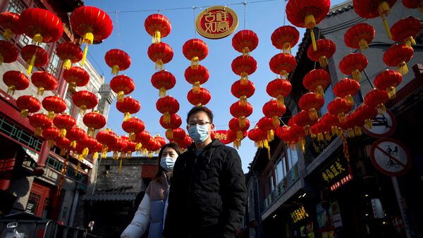 Люди гуляют под традиционными китайскими фонарями по аллее в Пекине. 9 февраля 2021 года