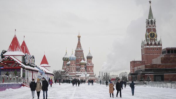Люди гуляют по выпавшему снегу на Красной площади в Москве