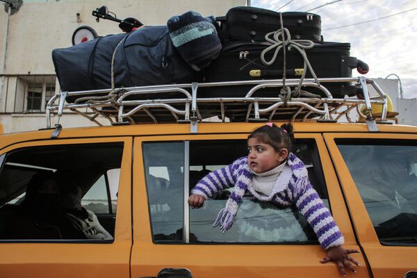 Девочка в окне автомобиля, который загружен чемоданами, в Секторе Газа