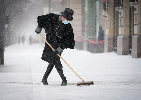 Портье отеля Adlon чистит улицу после снегопада в Берлине, Германия 