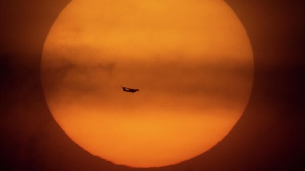 Летящий самолет на фоне заходящего солнца