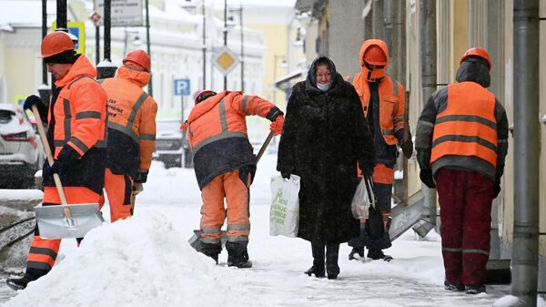 Сотрудники коммунальных служб убирают снег на улице в центре Москвы