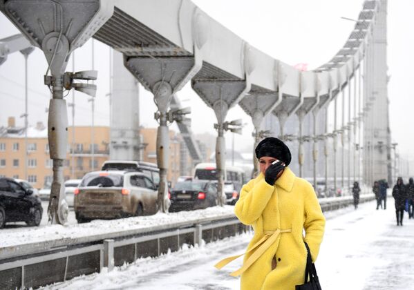 Девушка идет по Крымскому мосту во время снегопада в Москве