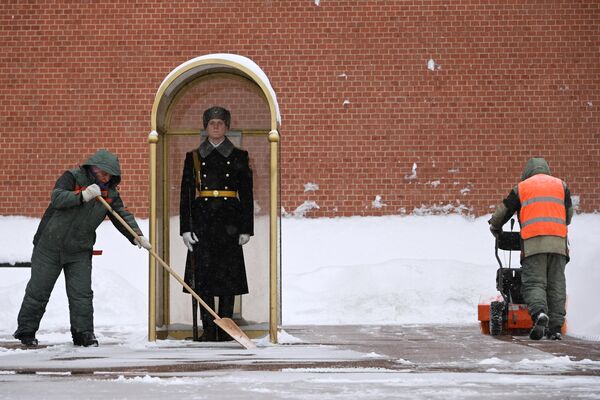 Сотрудники коммунальных служб убирают снег у поста Почётного караула у Вечного огня на Могиле Неизвестного Солдата в Александровском саду в Москве