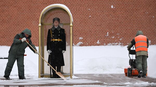 Сотрудники коммунальных служб убирают снег у поста Почётного караула у Вечного огня на Могиле Неизвестного Солдата в Александровском саду в Москве