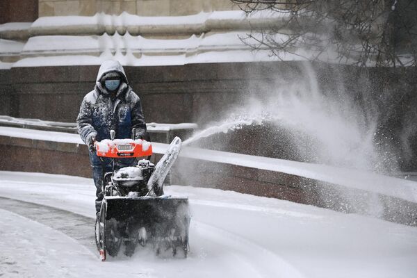 Сотрудник коммунальных служб убирает снег на улице в центре Москвы