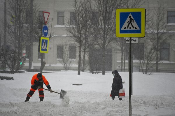 Сотрудник коммунальных служб чистит снег на улице Новинский бульвар в Москве