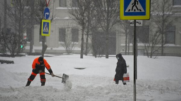 Сотрудник коммунальных служб чистит снег на улице Новинский бульвар в Москве