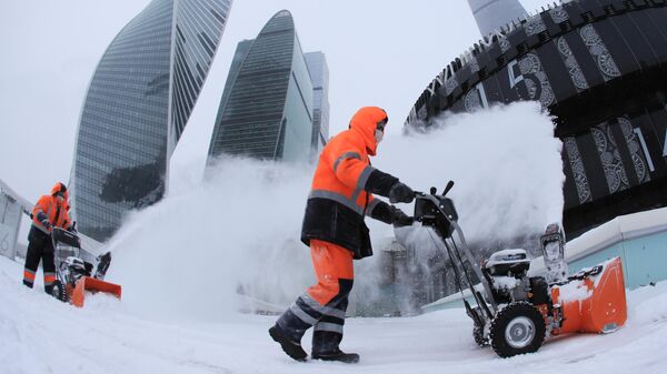 Сотрудники коммунальной службы убирают снег с площади у делового центра Москва-сити