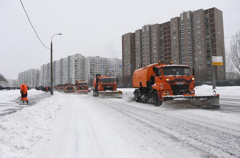 Сотрудники коммунальной службы убирают снег на улице в Москве во время снегопада