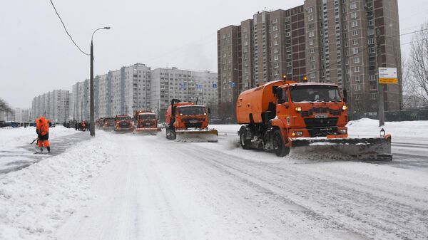 Сотрудники коммунальной службы убирают снег на улице в Москве во время снегопада
