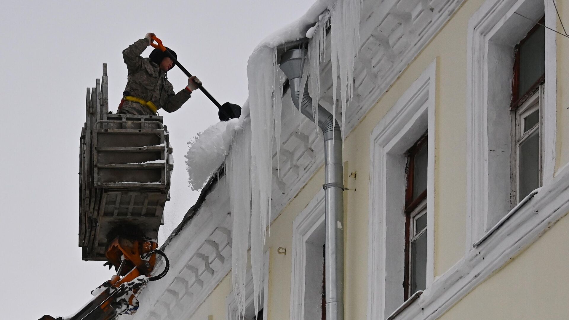 Сотрудник коммунальной службы счищает снег с крыши дома в Посланниковом переулке в Москве - РИА Новости, 1920, 23.01.2022