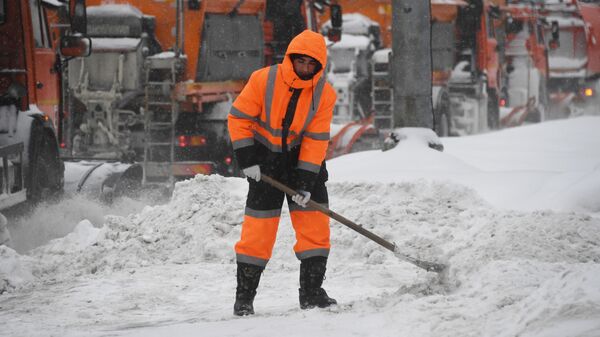 Сотрудник коммунальной службы убирает снег на улице в Москве во время снегопада.