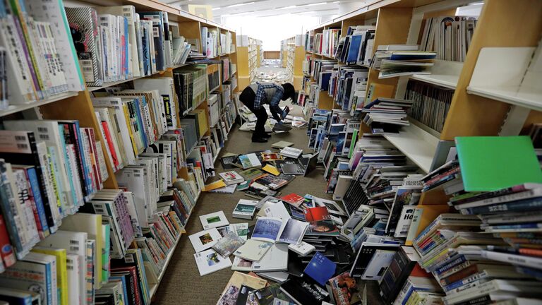 Сотрудник библиотеки убирается после сильного землетрясения в префектуре Фукусима, Япония. 14 февраля 2021 года