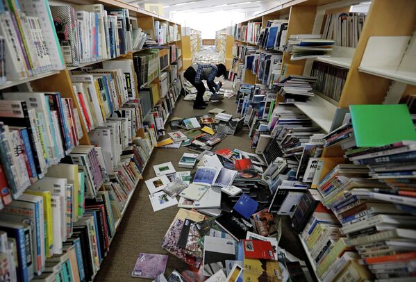 Сотрудник библиотеки убирается после сильного землетрясения в префектуре Фукусима, Япония. 14 февраля 2021 года