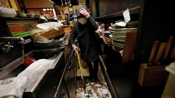 Владелица японского паба Идзакая, убирает разбитую посуду после сильного землетрясения в Иваки, префектура Фукусима, Япония. 14 февраля 2021 года