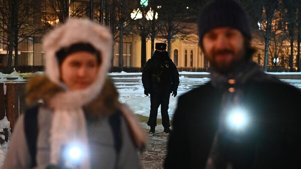 Сотрудник полиции наблюдает за порядком во время флешмоба с включенными фонариками в Москве