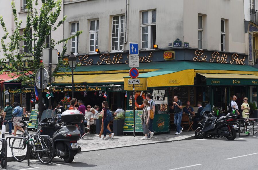 Горожане и туристы на улице Rue du Petit Pont рядом с пабом Cafe Le Petit Pont в Париже