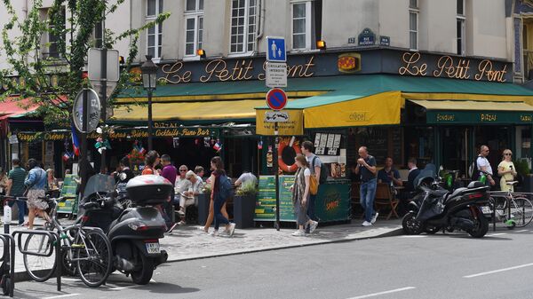 Горожане и туристы на улице Rue du Petit Pont рядом с пабом Cafe Le Petit Pont в Париже