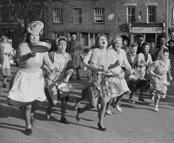 Британские домохозяйки бросают блины на сковородках во время ежегодного забега в Англии. 1951 год