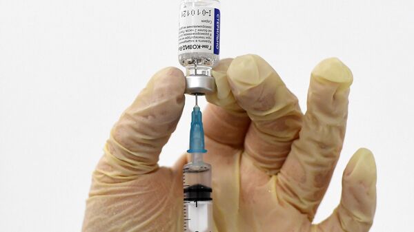 Медицинский работник держит в руках российскую вакцину Спутник V (Гам-КОВИД-Вак) в пункте вакцинации от коронавируса