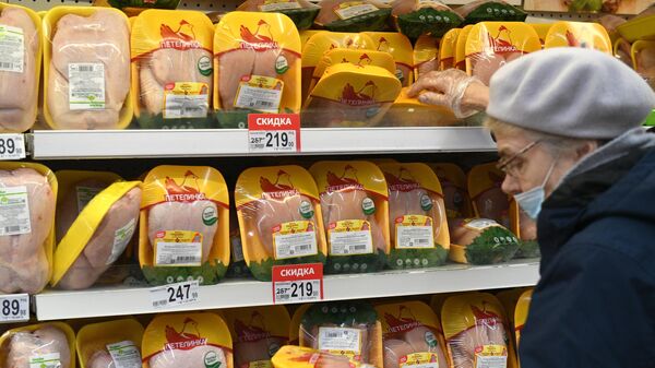 Покупательница выбирает курицу в мясном отделе гипермаркета Ашан в Москве