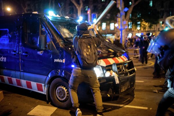 Протестующий бьет битой полицейский фургон во время столкновений после акции протеста в Барселоне