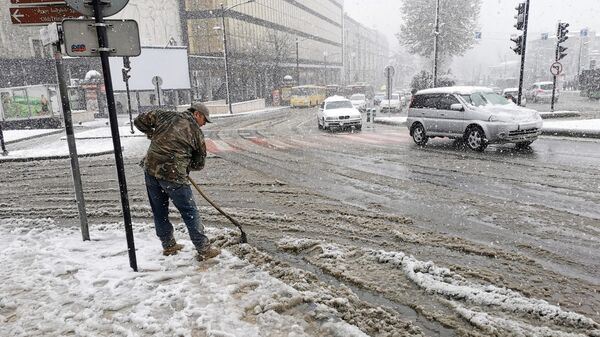 Сотрудник коммунальных служб убирает снег на дорогах после снегопада в Тбилиси