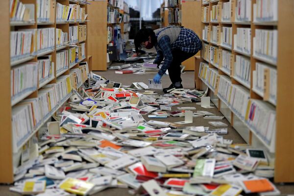 Сотрудник библиотеки убирается после сильного землетрясения в городе Иваки