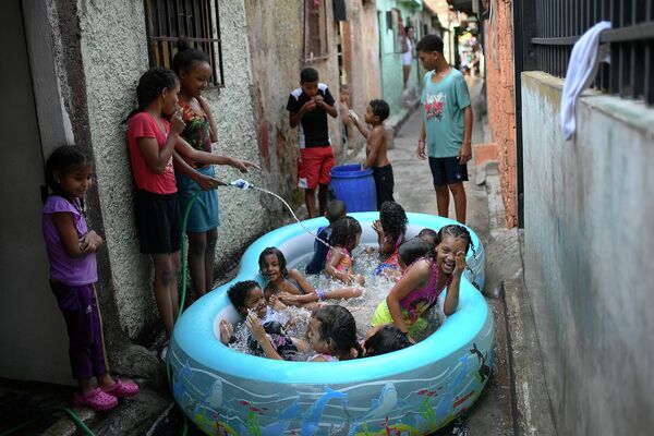 Дети купаются в надувном бассейне в Каракасе, Венесуэла 