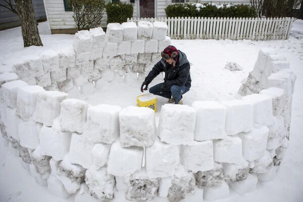 Мужчина строит иглу из снега после снегопада в Огайо, США 