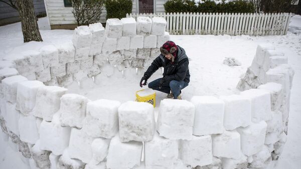 Мужчина строит иглу из снега после снегопада в Огайо, США 