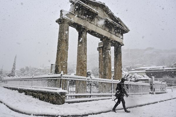 Мужчина проходит мимо Римской Агоры во время сильного снегопада в Афинах