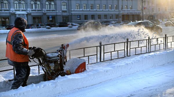 Сотрудник коммунальной службы во время уборки снега после метели на улице Омска