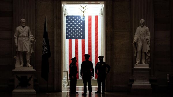 Офицеры полиции стоят перед американским флагом в ротонде Капитолия США в Вашингтоне