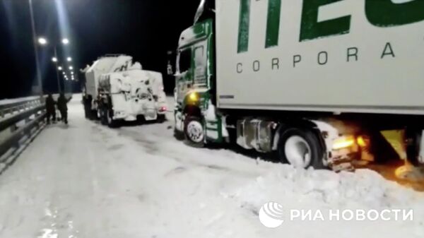 Военные Черноморского флота помогают вытаскивать из снега грузовой автомобиль на трассе в Крыму. Кадр видео