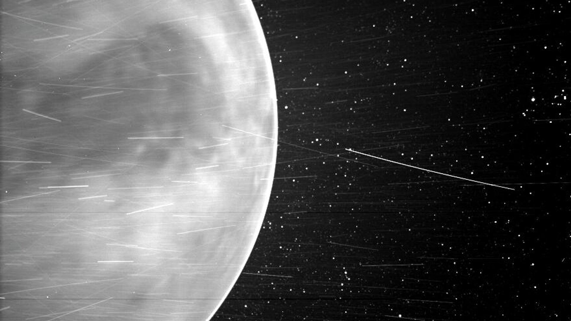 Изображение Венеры и светящейся полоски в ее атмосфере, сделанное прибором WISPR солнечного зонда NASA Parker в июле 2020 года. Темная область в центре изображения - Земля Афродиты, самый большой горный регион на поверхности Венеры. Яркие полосы вызваны заряженными частицами солнечного ветра, отраженными частицами космической пыли и частицами материала космического корабля - РИА Новости, 1920, 25.02.2021