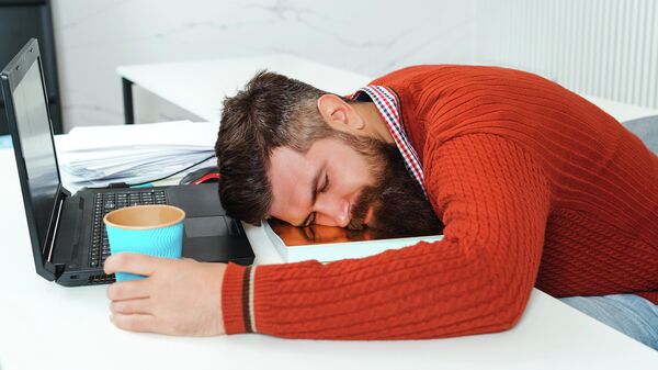 Уставший бизнесмен спит в офисе