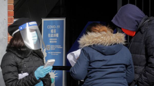 Медицинский работник помогает людям записываться на прием для получения вакцины против коронавируса (COVID-19) в Нью-Йорке, США