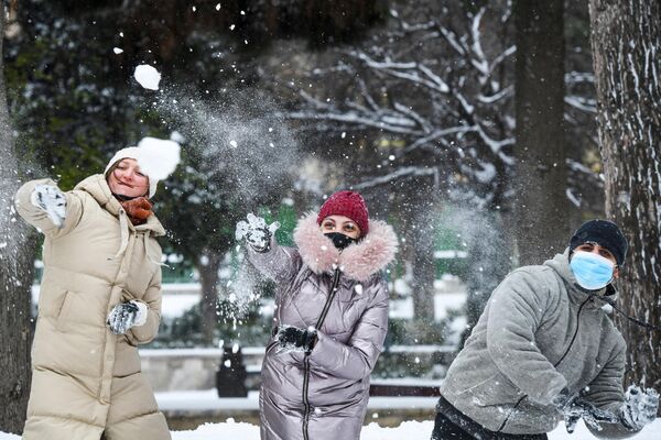 Прохожие играют в снежки на одной из улиц в Баку во время снегопада
