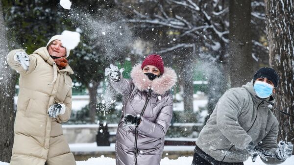 Прохожие играют в снежки на одной из улиц в Баку во время снегопада