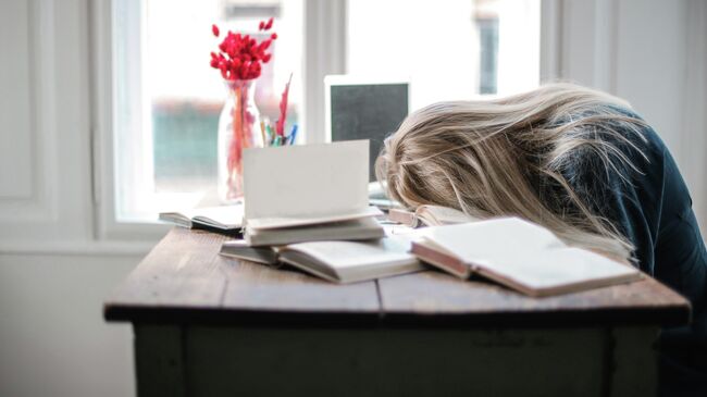 Молодая женщина спит за рабочим столом. Архивное фото