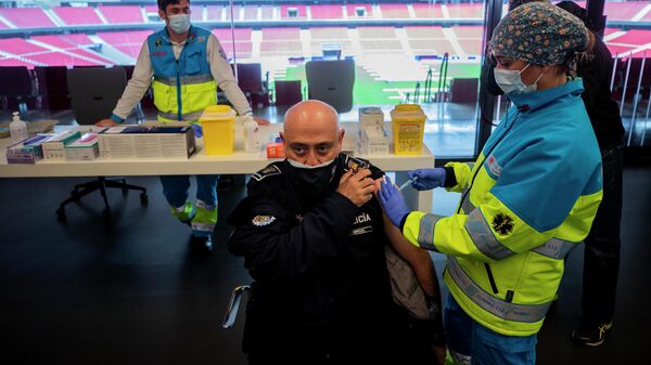 Полицейский во время инъекции вакцины AstraZeneca против COVID-19 в Мадриде